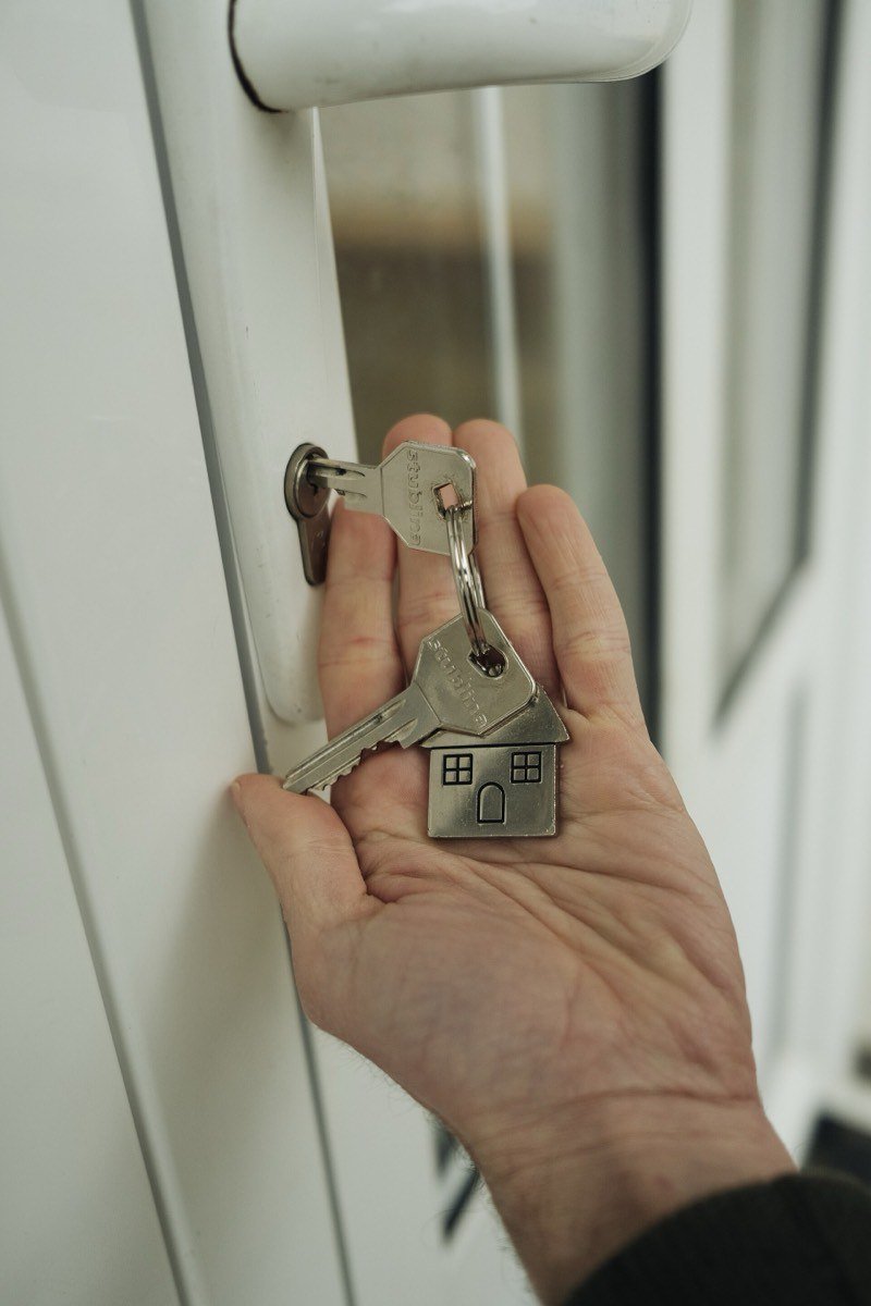 A hand holding house keys at a front door — the next chapter after a hard year